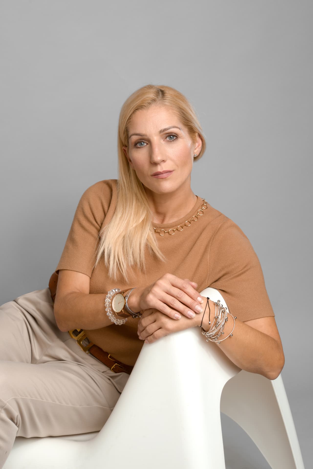 Fodor Anita pénzügyi tanácsadó barna pulóverben, világos térben ülve