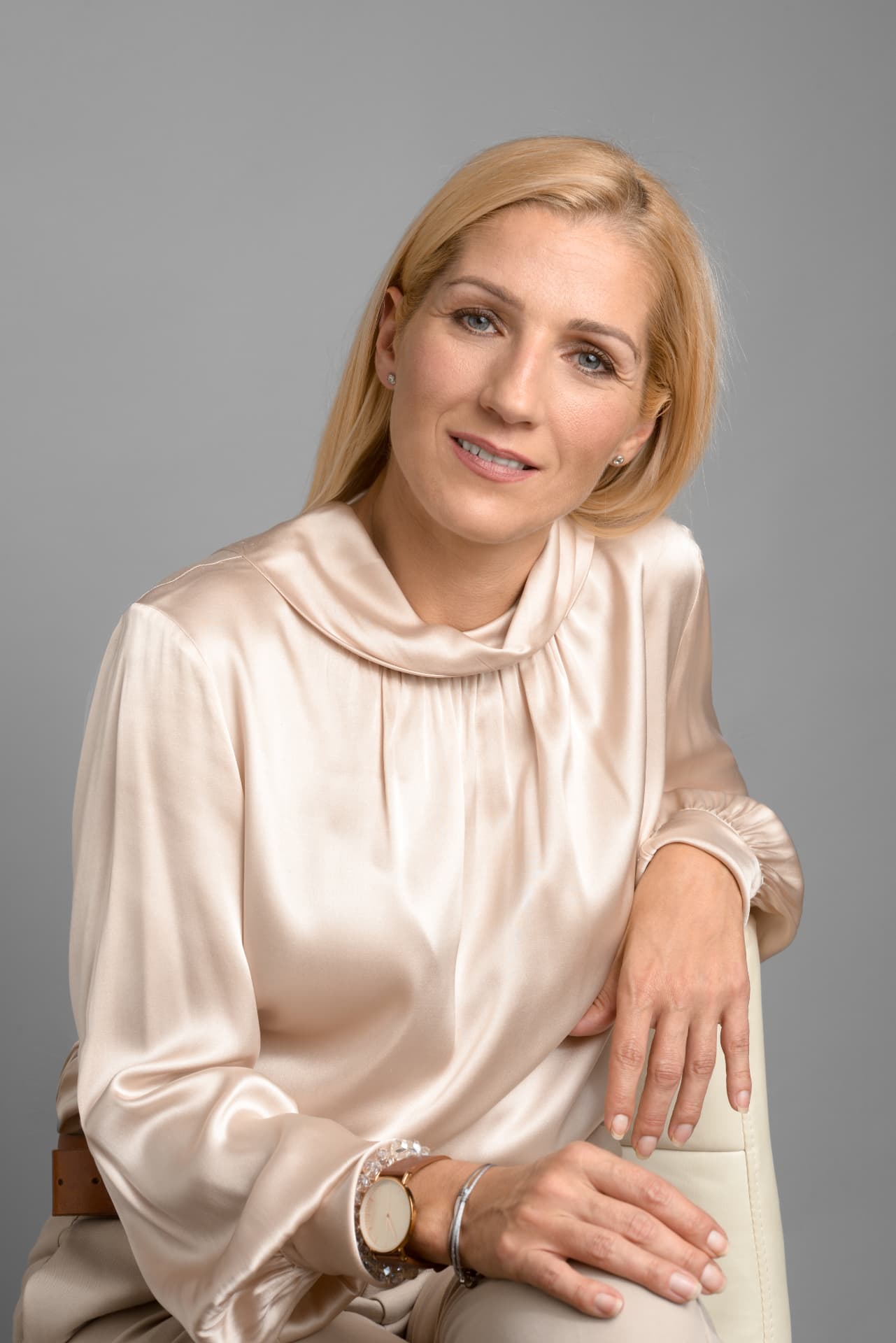 Fodor Anita krémszínű blúzban, székre támaszkodva